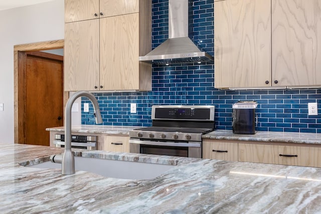 kitchen featuring wall chimney range hood, light brown cabinets, decorative backsplash, and stainless steel range oven