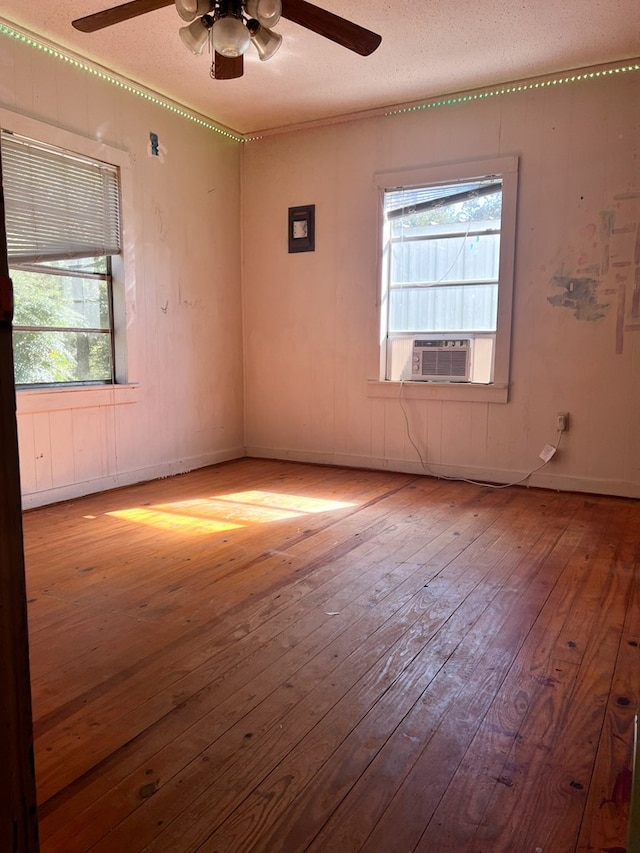 unfurnished room with a wealth of natural light, a textured ceiling, and light wood-type flooring