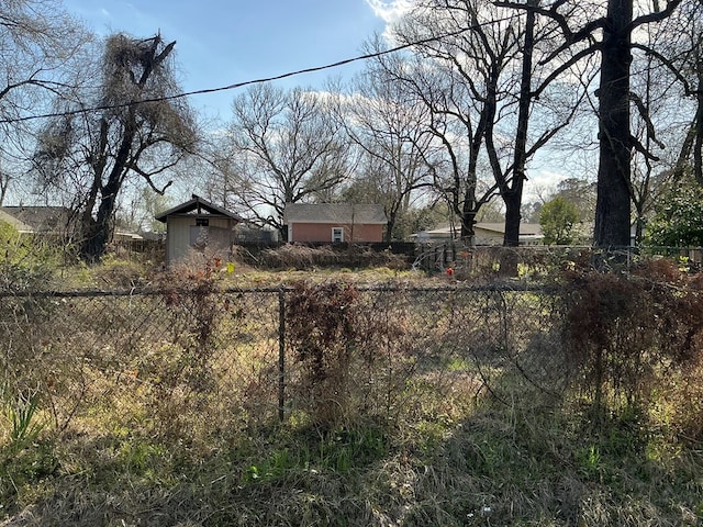 view of yard featuring a storage shed, an outbuilding, and fence