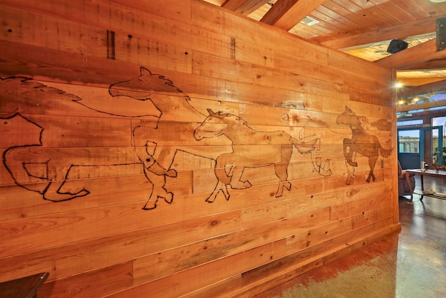 interior space featuring wood walls, beamed ceiling, concrete floors, and wooden ceiling