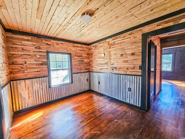 unfurnished room with hardwood / wood-style flooring, a wealth of natural light, and wood walls