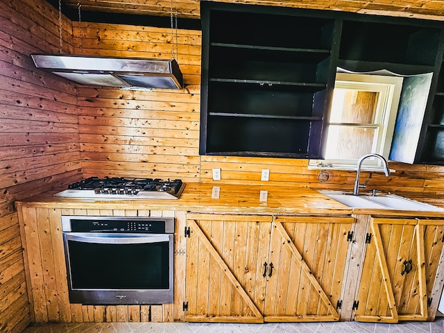1026 Berry Rd, Lufkin, TX 75904 - kitchen with appliances with stainless steel finishes, extractor fan, wood walls, and butcher block countertops
