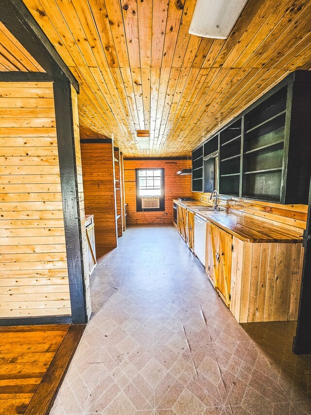 interior space featuring white dishwasher, wooden ceiling, sink, and wooden walls