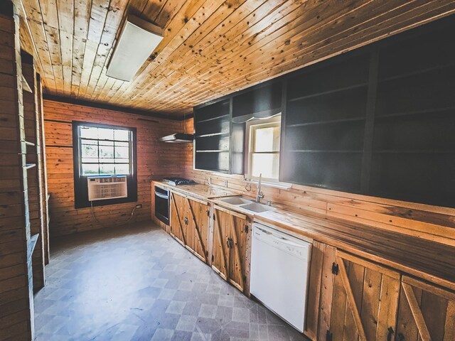 kitchen featuring white dishwasher, oven, wooden walls, and sink