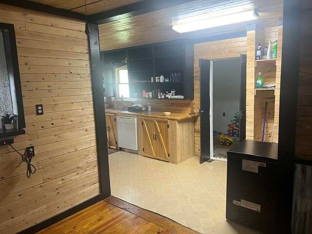 kitchen with wooden counters, white dishwasher, wooden walls, and light hardwood / wood-style floors