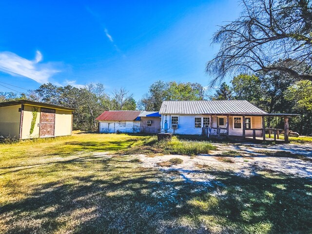 ranch-style home with covered porch, an outdoor structure, and a front lawn