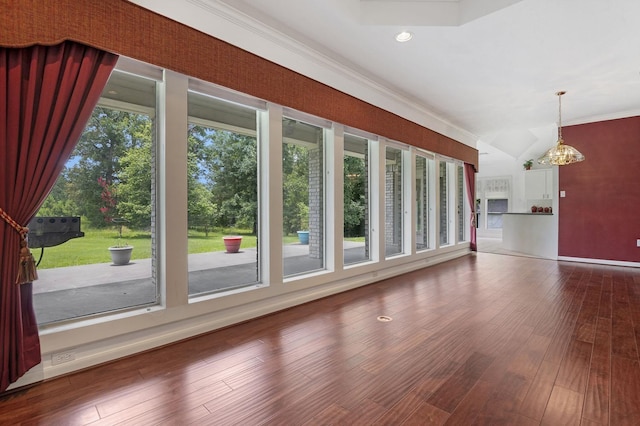 unfurnished living room featuring hardwood / wood-style floors, plenty of natural light, crown molding, and an inviting chandelier