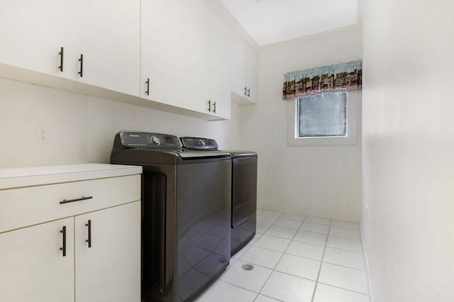 laundry room featuring cabinets, light tile patterned floors, and washing machine and clothes dryer