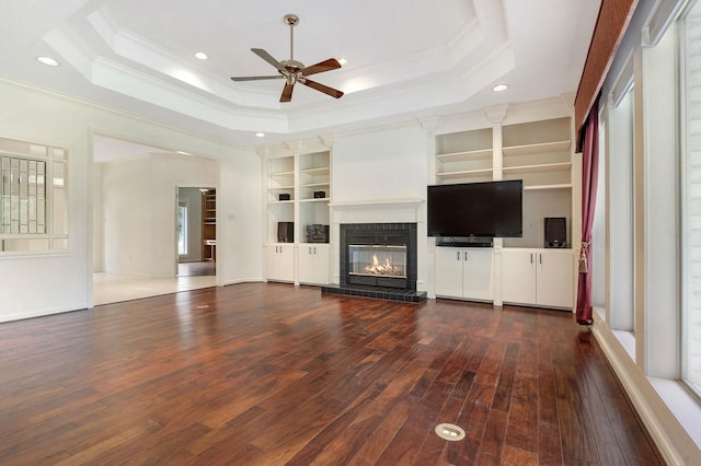 unfurnished living room featuring hardwood / wood-style floors, a tray ceiling, and ornamental molding