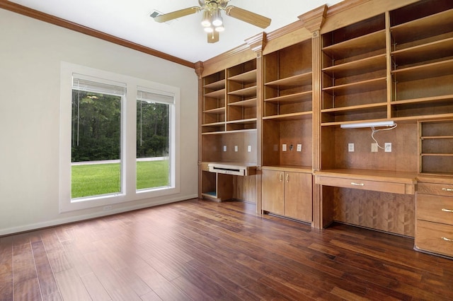 unfurnished office featuring ceiling fan, crown molding, built in desk, and dark wood-type flooring