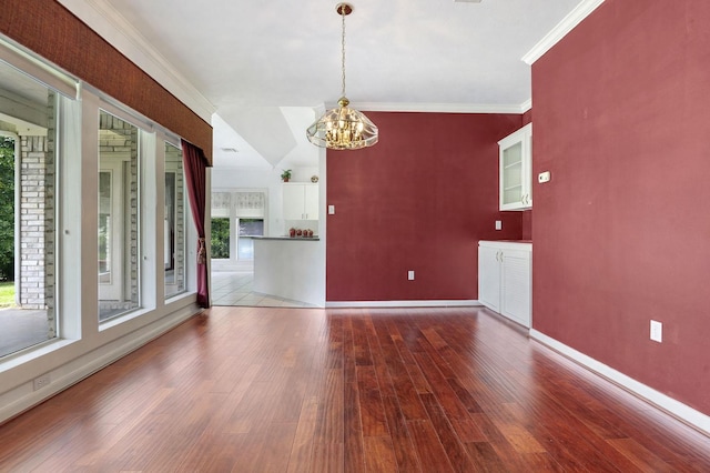 empty room with a wealth of natural light, crown molding, and wood-type flooring