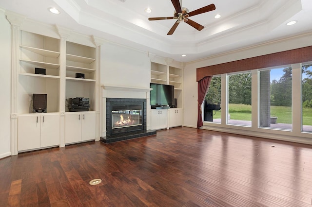 unfurnished living room featuring a tile fireplace, dark hardwood / wood-style flooring, built in features, and ornamental molding