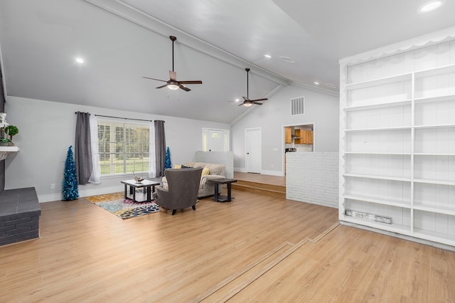 living room with lofted ceiling with beams, light wood-type flooring, and a fireplace