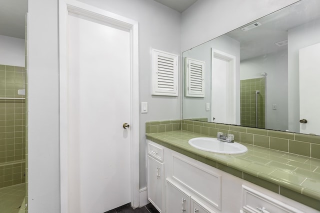 bathroom featuring vanity, tiled shower, and tasteful backsplash