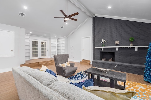 living room with vaulted ceiling with beams, ceiling fan, light hardwood / wood-style flooring, and a brick fireplace