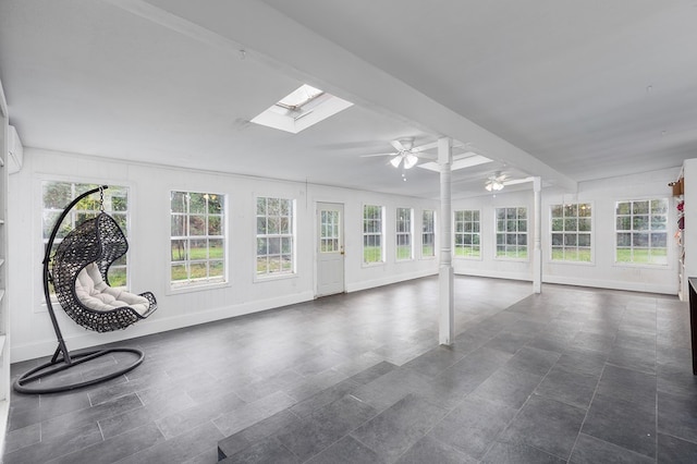 unfurnished sunroom featuring beam ceiling, a skylight, and ceiling fan