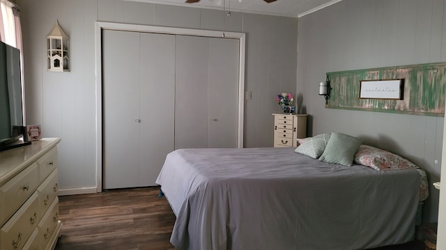 bedroom featuring wooden walls, a closet, dark wood-type flooring, and ornamental molding