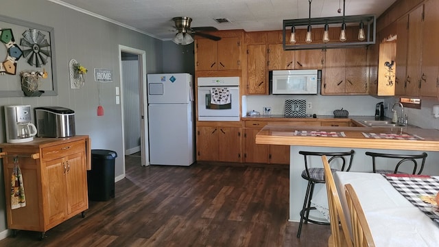 kitchen featuring white appliances, dark wood-type flooring, crown molding, sink, and ceiling fan