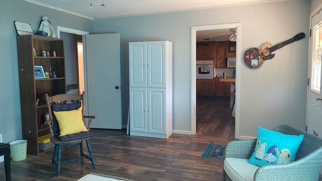 sitting room featuring dark hardwood / wood-style floors, crown molding, and wooden walls