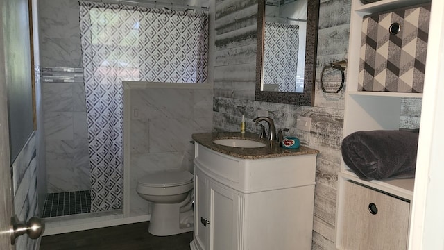 bathroom featuring a tile shower, vanity, hardwood / wood-style flooring, tile walls, and toilet