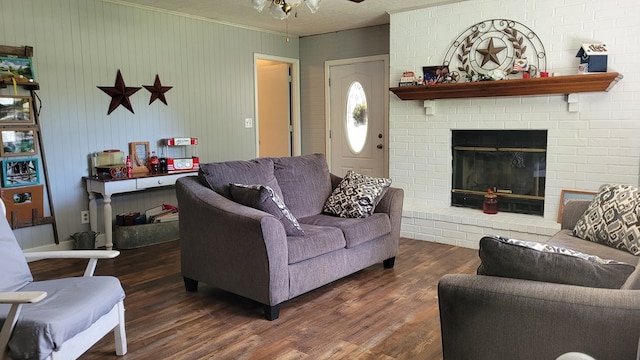 living room featuring ceiling fan, dark wood-type flooring, a textured ceiling, and a brick fireplace