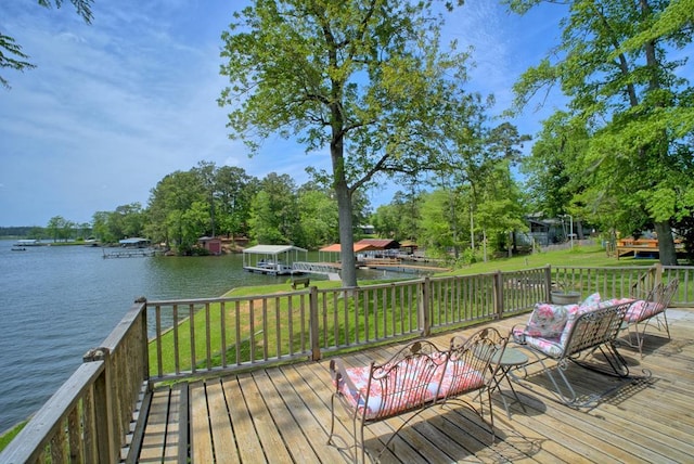 wooden deck with a lawn, a water view, and a dock