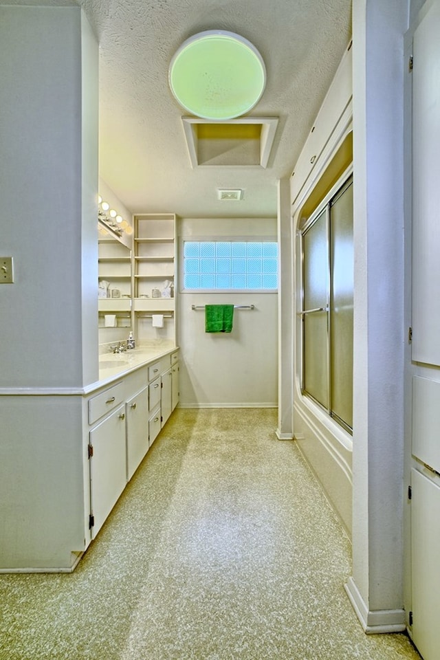 full bathroom with a textured ceiling, combined bath / shower with glass door, vanity, carpet, and baseboards
