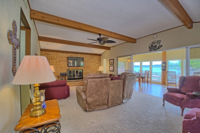 carpeted living room with ceiling fan, a brick fireplace, and vaulted ceiling with beams