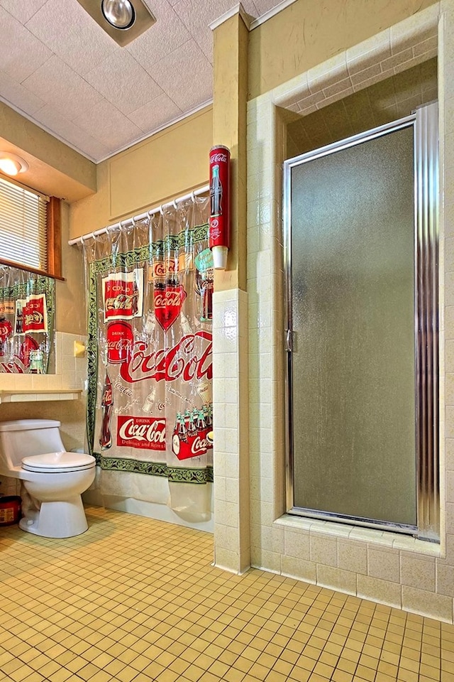 full bath featuring tile walls, a wainscoted wall, and toilet