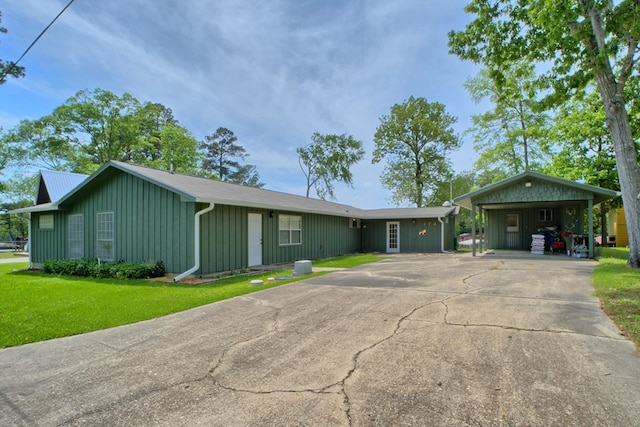 ranch-style home with board and batten siding, a front lawn, a carport, and concrete driveway