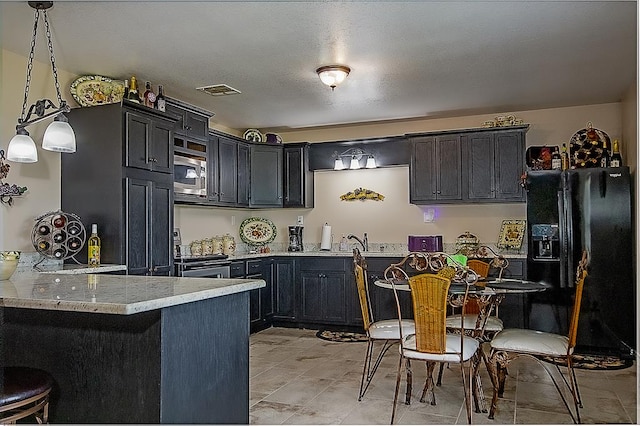 kitchen featuring sink, hanging light fixtures, light stone countertops, appliances with stainless steel finishes, and kitchen peninsula