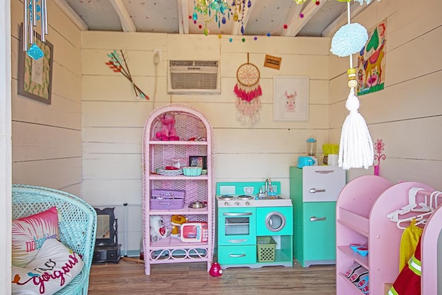 playroom featuring hardwood / wood-style floors and an AC wall unit