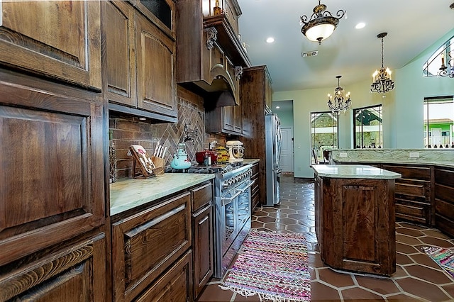 kitchen featuring backsplash, a notable chandelier, a kitchen island, dark brown cabinetry, and stainless steel appliances