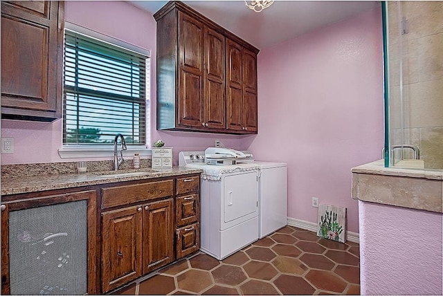 laundry area with washer and clothes dryer, sink, cabinets, and dark tile patterned flooring