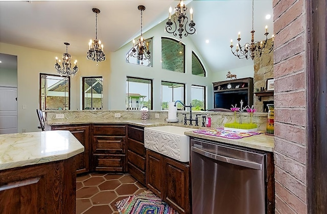 kitchen with light stone counters, stainless steel dishwasher, vaulted ceiling, sink, and a fireplace