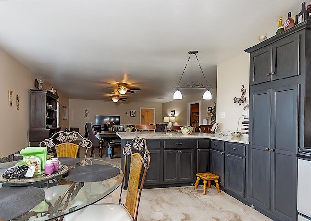 kitchen with light stone countertops, kitchen peninsula, ceiling fan, and hanging light fixtures