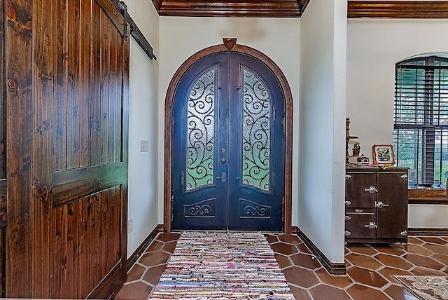 tiled foyer entrance featuring french doors, a barn door, and crown molding