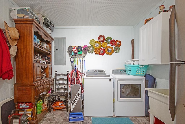 washroom featuring electric panel, washer and clothes dryer, and cabinets