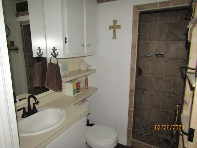 bathroom featuring tiled shower, vanity, and toilet