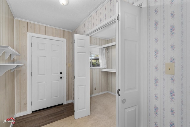 entryway with hardwood / wood-style flooring, crown molding, a textured ceiling, and wooden walls