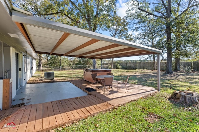 deck with a hot tub, cooling unit, and a lawn