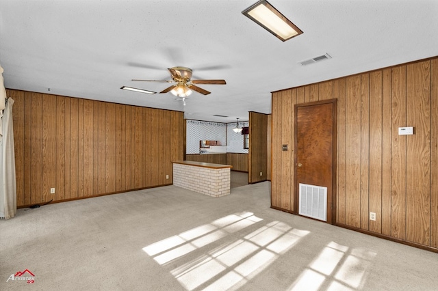 interior space with ceiling fan, wood walls, and a textured ceiling