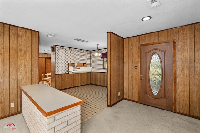 carpeted entryway with a textured ceiling and wood walls