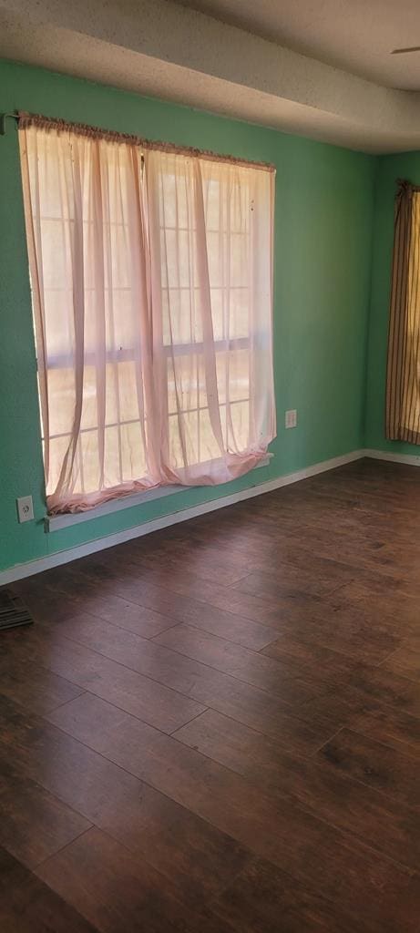 unfurnished room featuring baseboards and dark wood finished floors