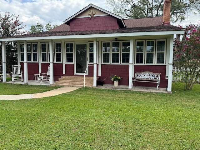 view of front of house with entry steps, a chimney, a shingled roof, and a front lawn