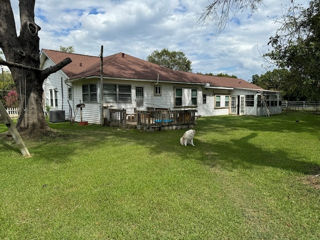 rear view of property featuring a yard, a deck, and central air condition unit