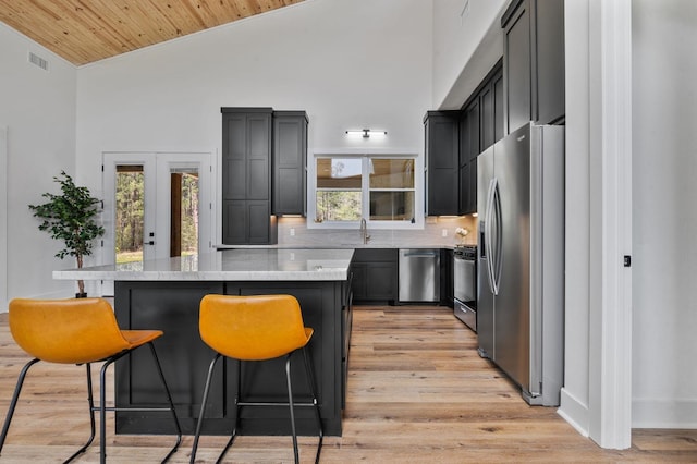 kitchen featuring french doors, wooden ceiling, stainless steel appliances, a breakfast bar area, and light wood-type flooring