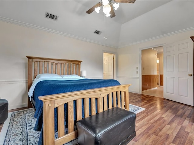 bedroom featuring a ceiling fan, visible vents, light wood-style floors, and ornamental molding
