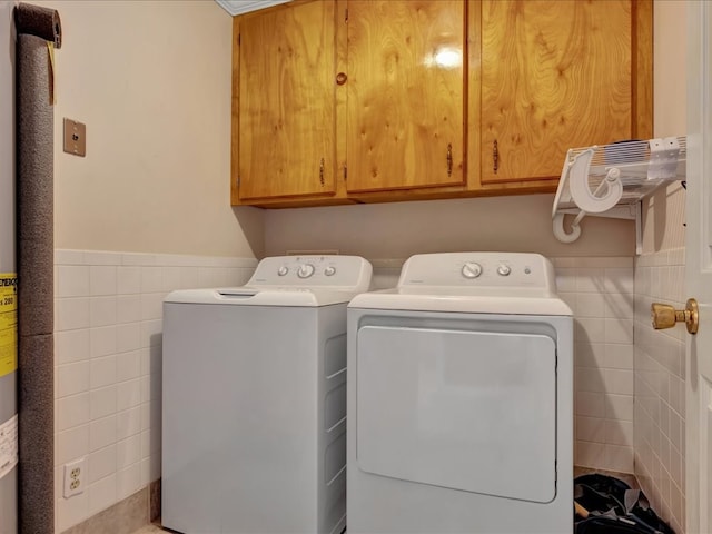 laundry room with cabinet space, independent washer and dryer, tile walls, and wainscoting