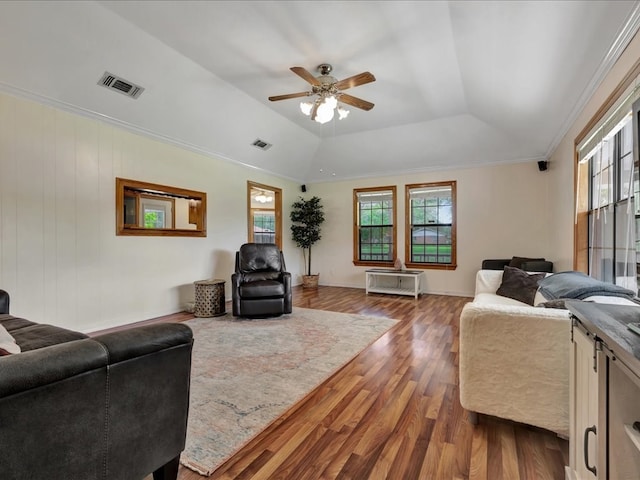 living room featuring a raised ceiling, wood finished floors, visible vents, and a ceiling fan